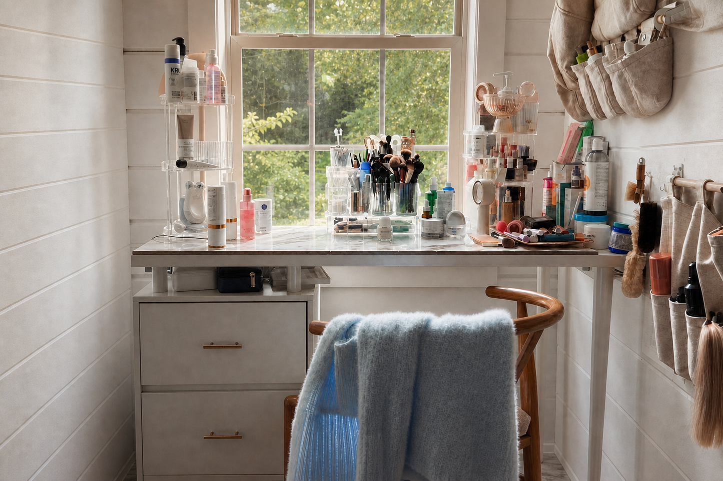 A lived-in cabin vanity beside a leafy window with a blue sweater draped over the chair.