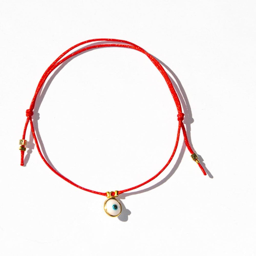 Classic evil eye bracelet on red string with a small gold hamsa charm by Sunday Forever