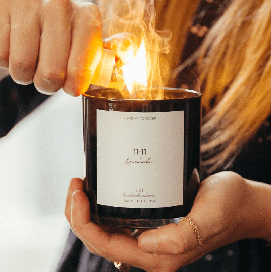 Hands lighting an 11:11 candle with the flame catching by Sunday Forever
