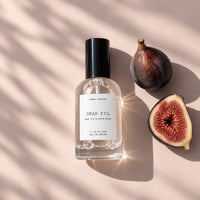Dear Fig, Eau de Parfum lying in warm light beside a whole fig and a cut fig by Sunday Forever