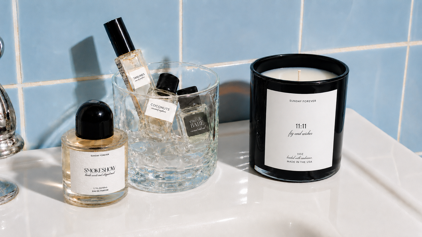 Smokeshow perfume and 11:11 candle on a bathroom counter with a tray of Try Me perfumes